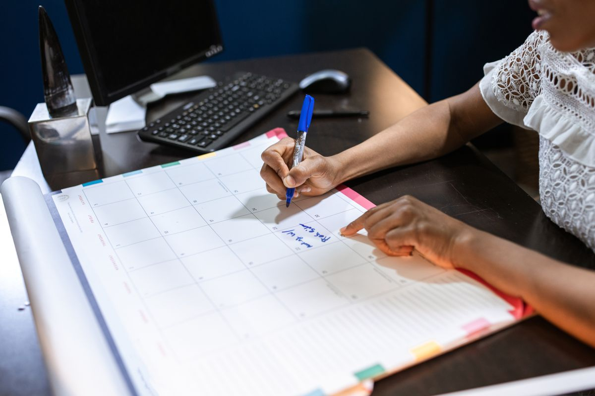 Small business owner planning schedule and recurring tasks on desk calendar